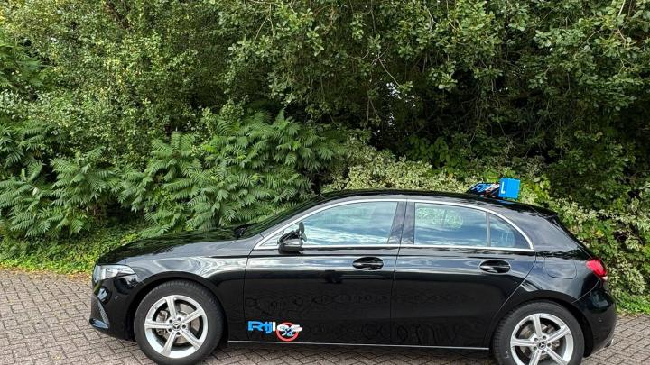 Zwarte lesauto van Rijles32 met een L-bord op het dak