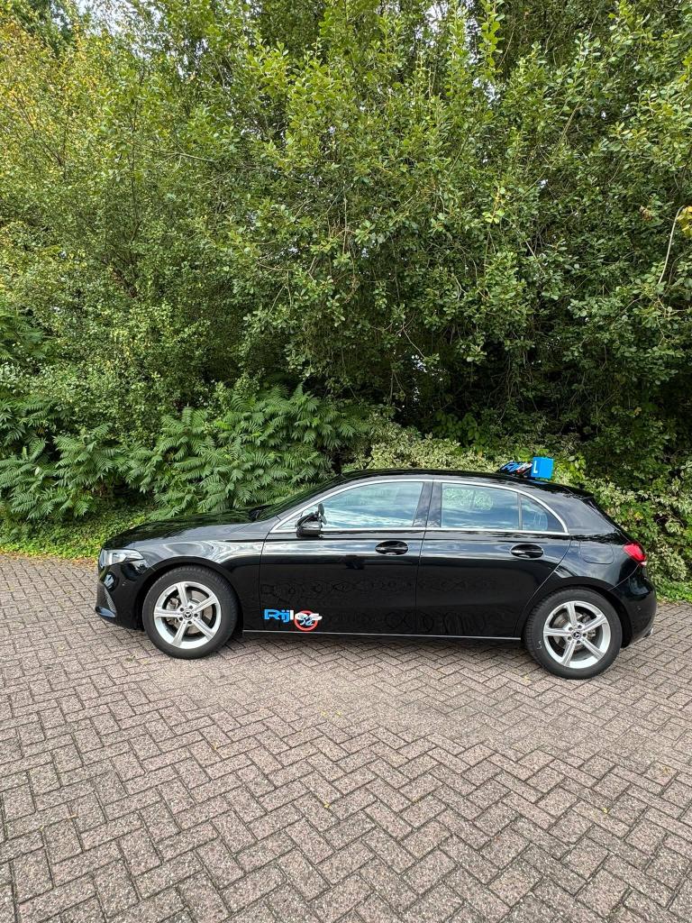 Zwarte lesauto van Rijles32 met een L-bord op het dak